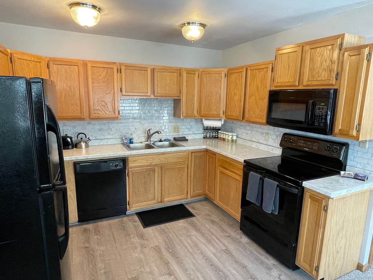 Kitchen with oak cabinets, a black range, microwave and dishwasher and a subway-tile backsplash