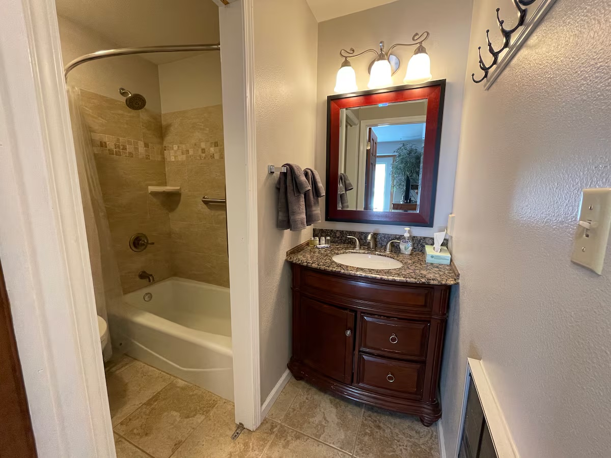 Bathroom with a dark wood vanity, a framed mirror and a tiled tub and shower