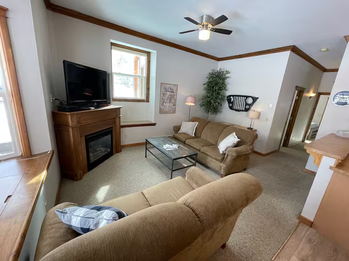 Living room with a gas fireplace, a television on the mantel and two upholstered sofas