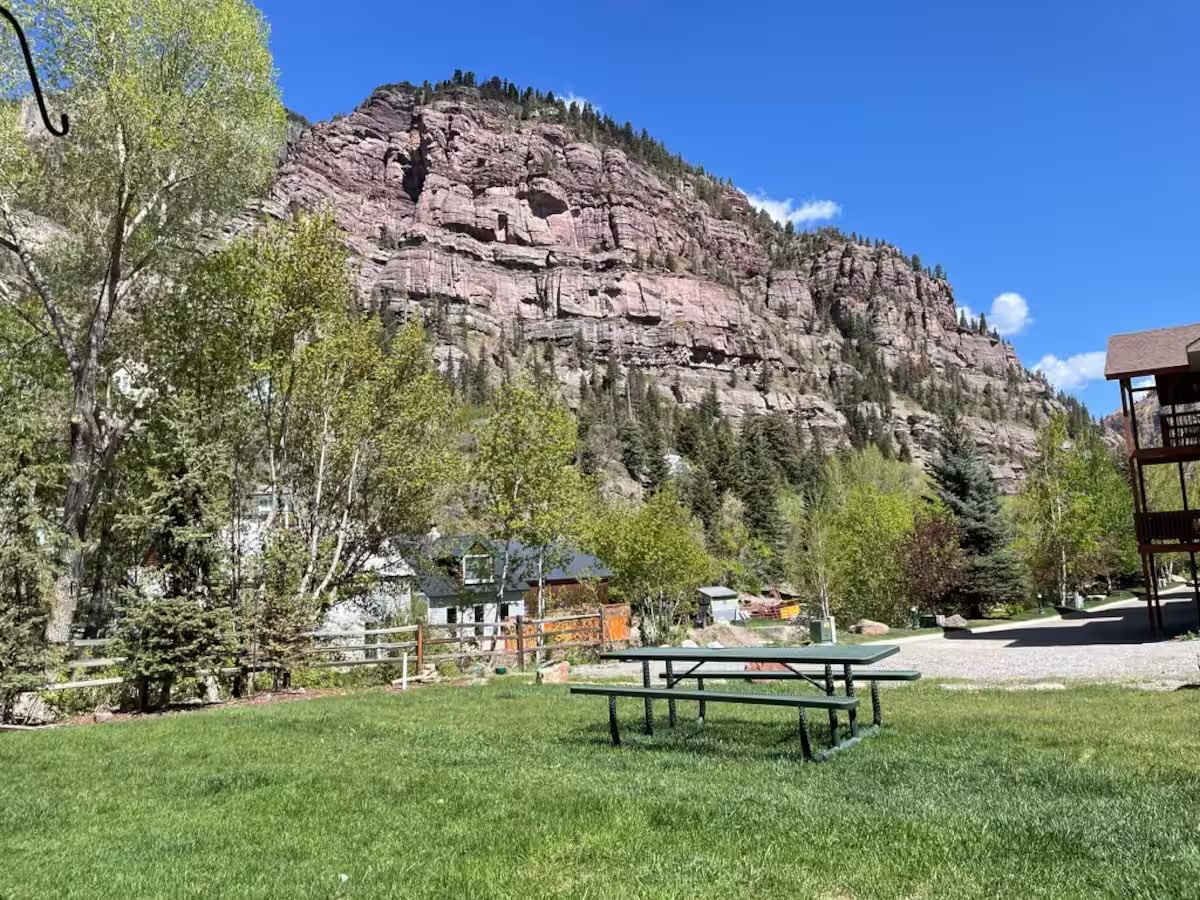 Lawn and picnic table outside the building, with the canyon wall behind