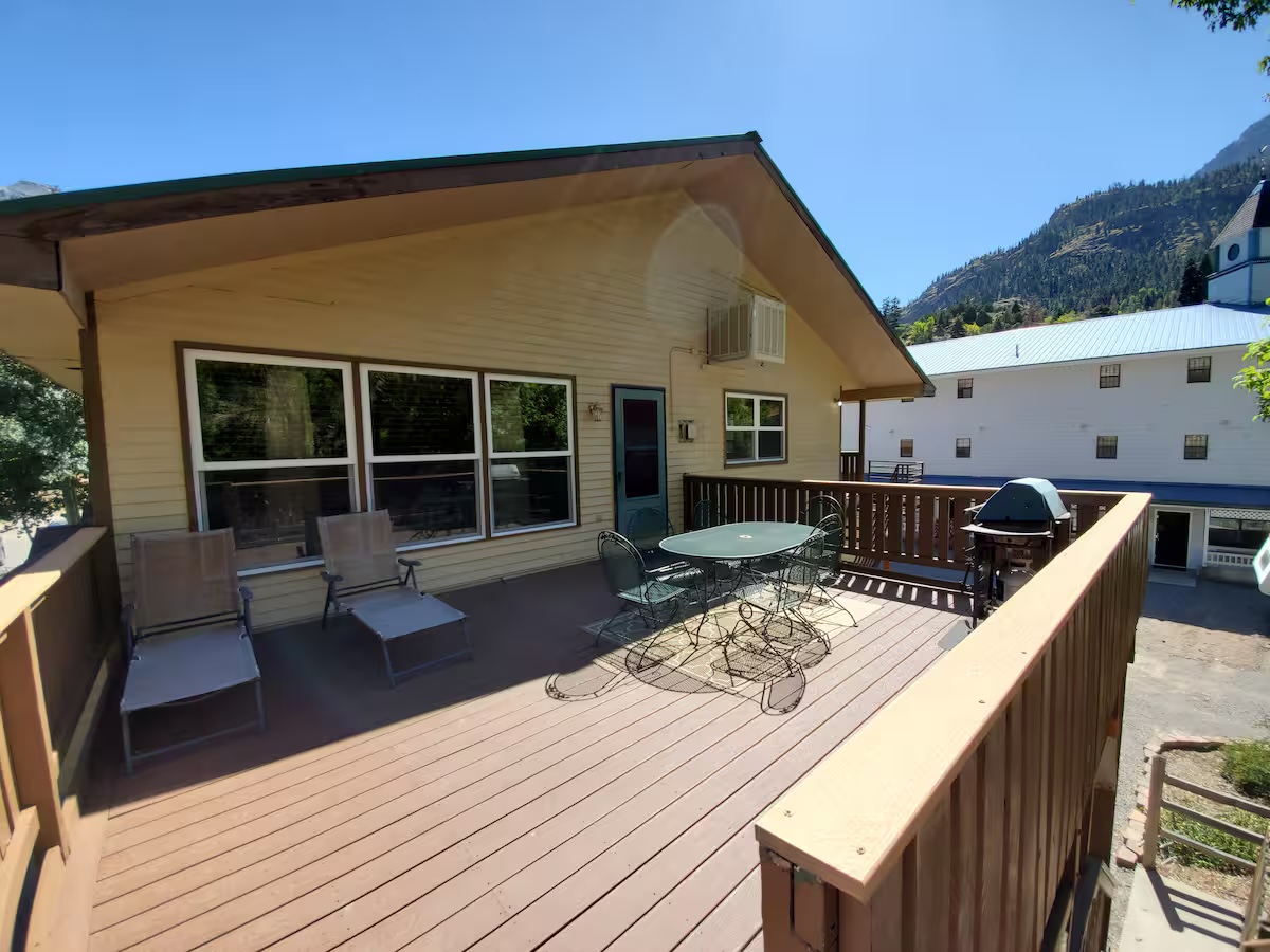 Deck with a patio table, lounge chairs and a gas grill, with the mountains beyond