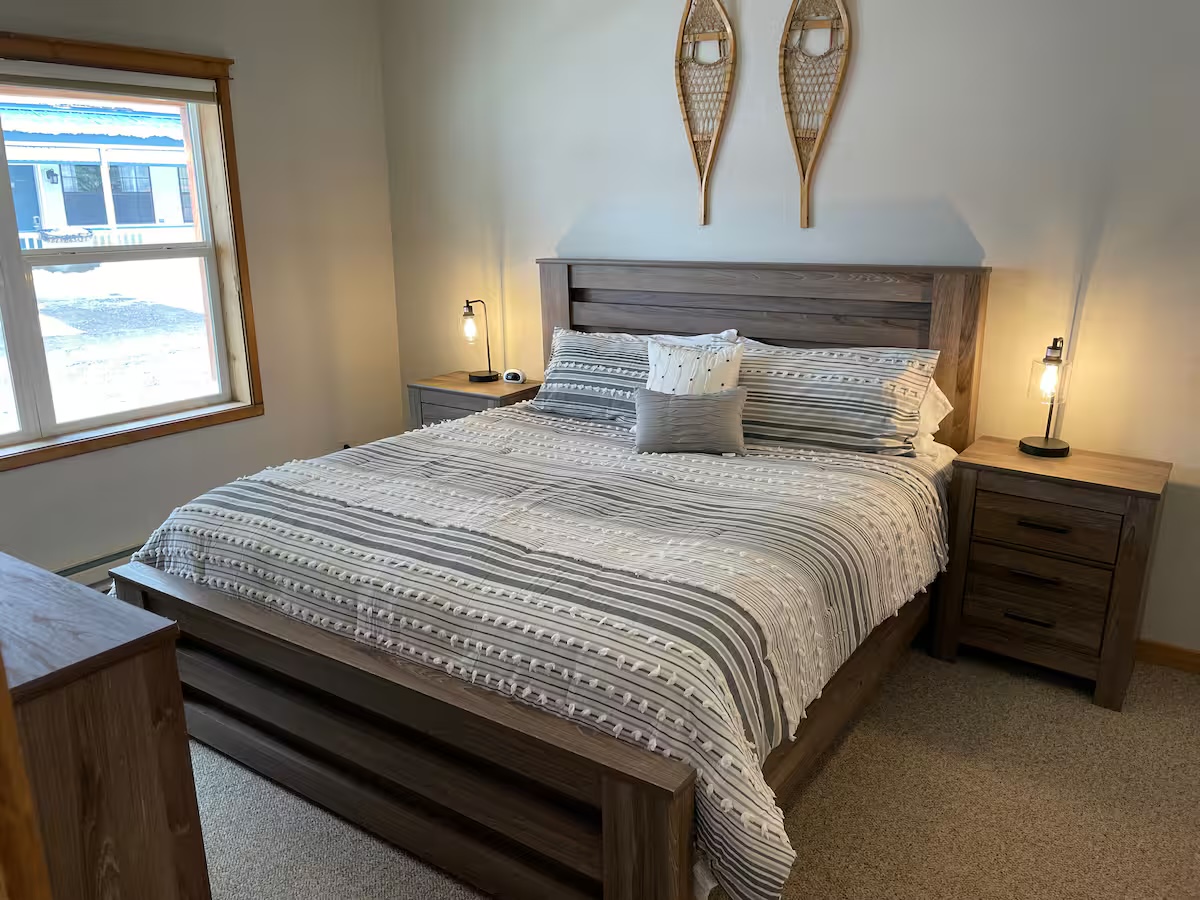 Bedroom with a wood headboard, bedside lamps and snowshoes mounted above the bed