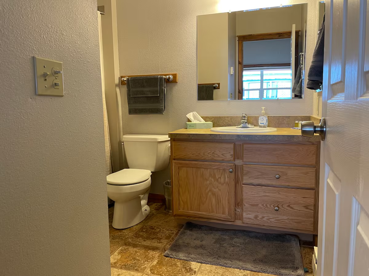 Bathroom with an oak vanity, a tub and shower and a tiled floor